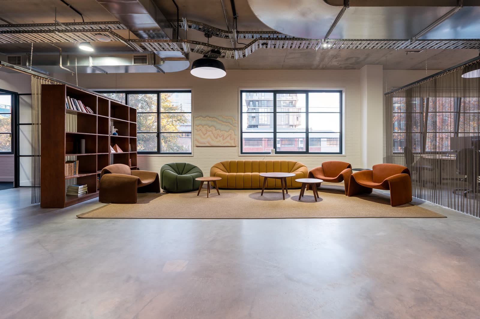 An office breakout lounge with curved sofas, armchairs and open shelving