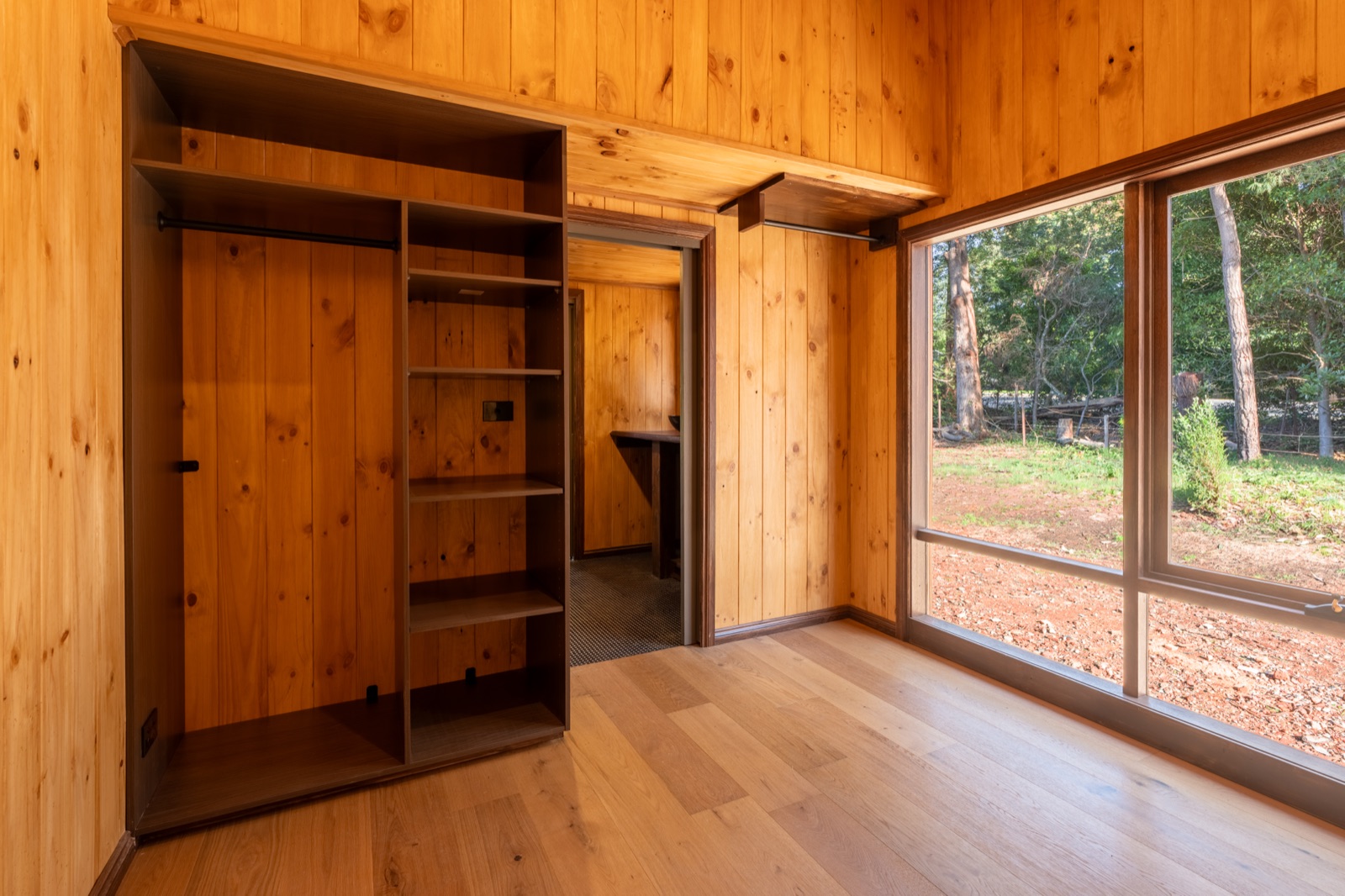 Built in timber shelving and a wardrobe in a tiny home bedroom