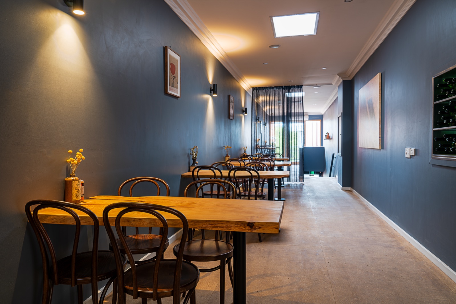 The dining room of a wine bar in deep navy with bentwood chairs