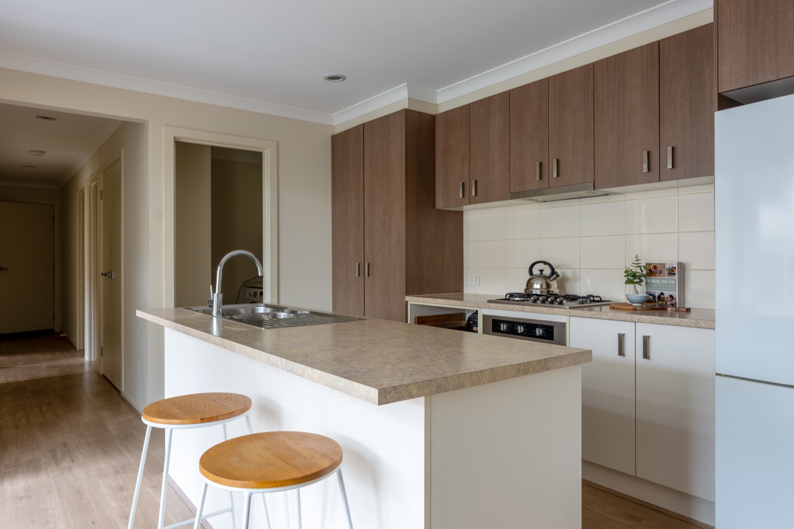 A new residential kitchen with a stone island bench and timber stools