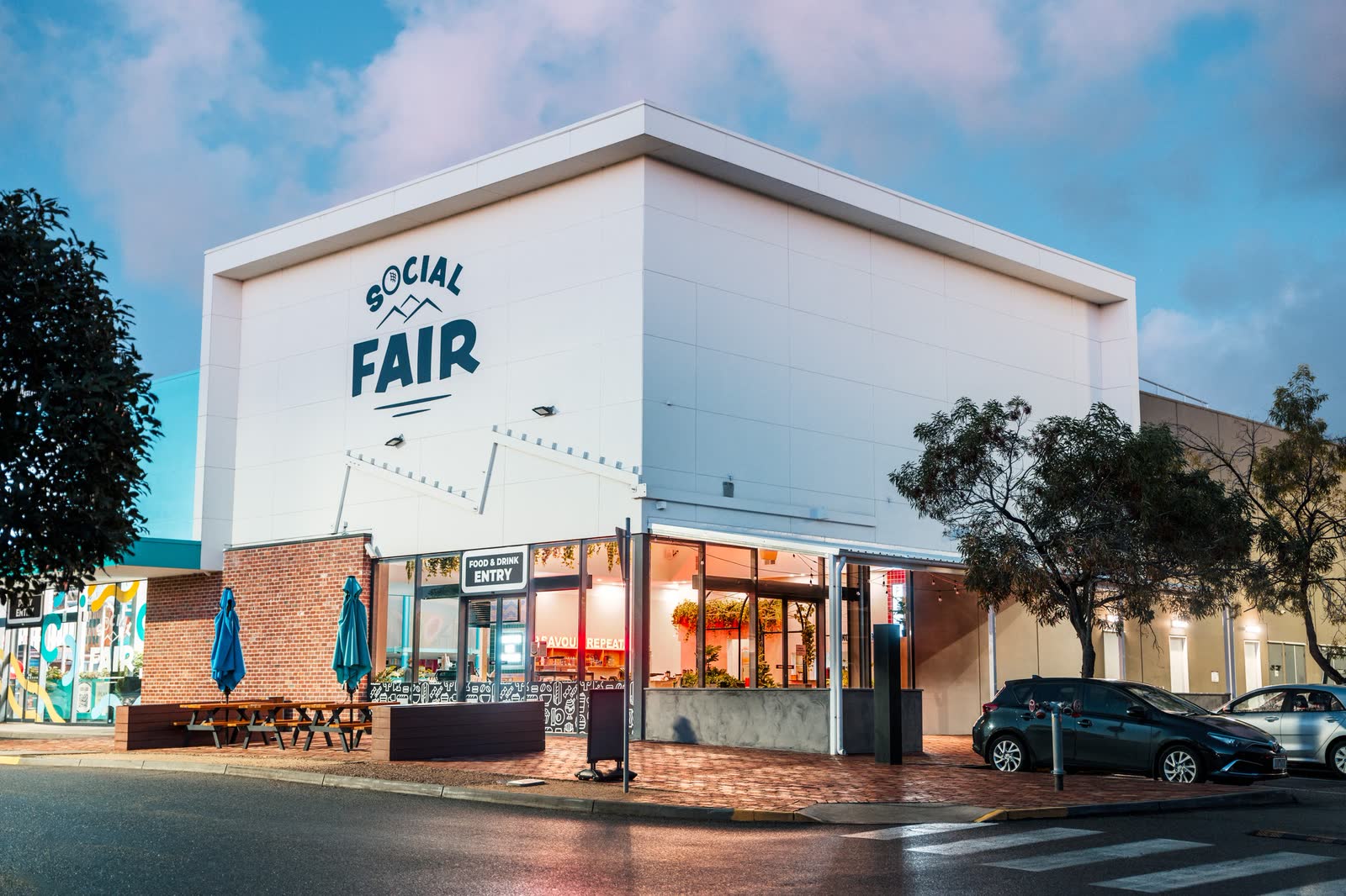 The Social Fair building and its lit shopfronts at dusk