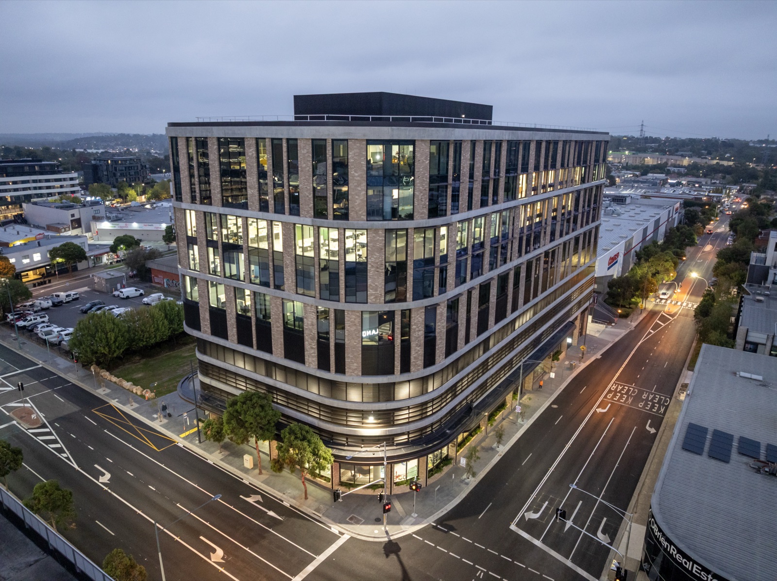 Aerial of the Top Glaze Ringwood office building lit at dusk on its corner site