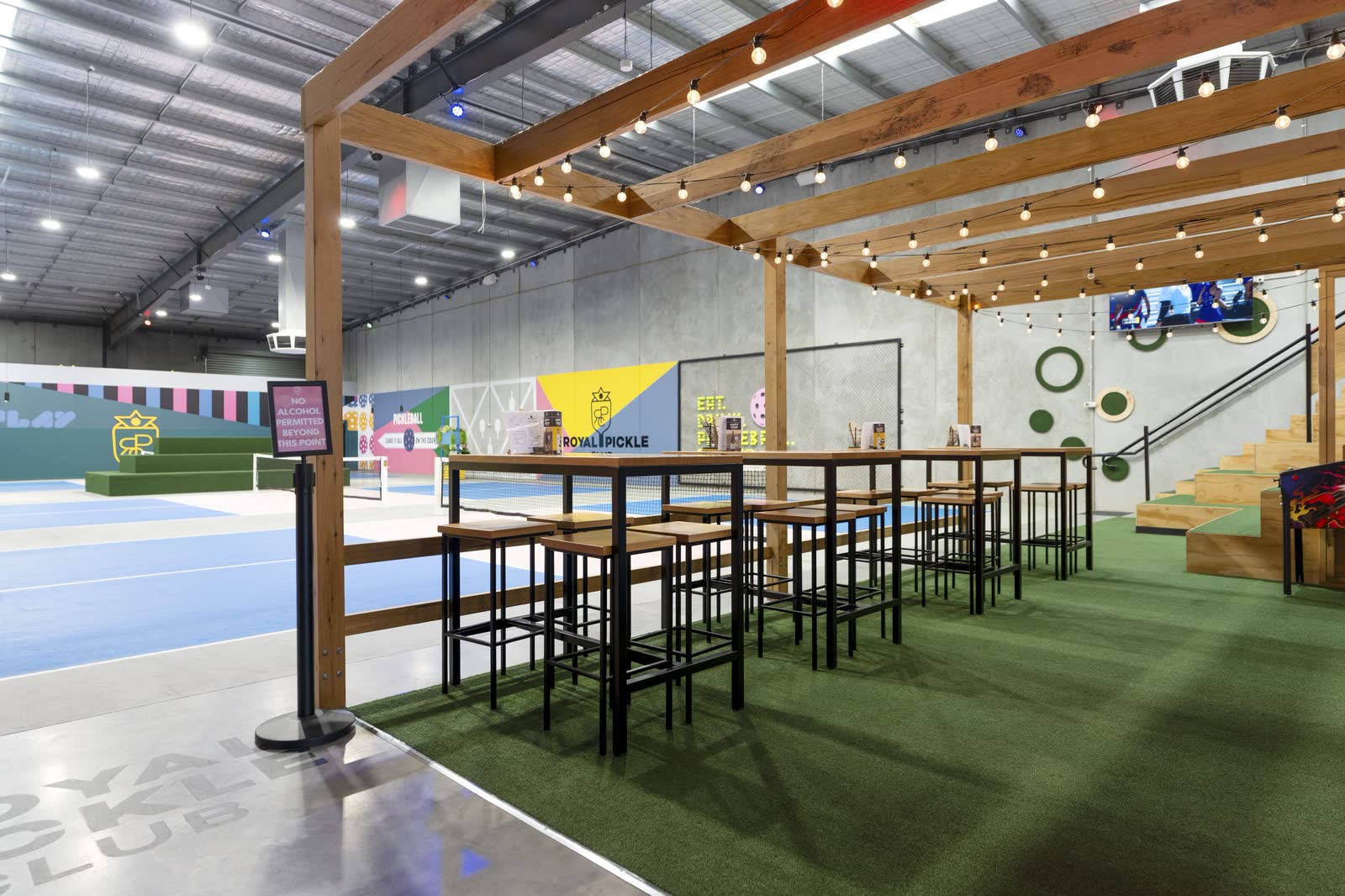 Tiered seating and a timber pergola overlooking the courts at Royal Pickle Club