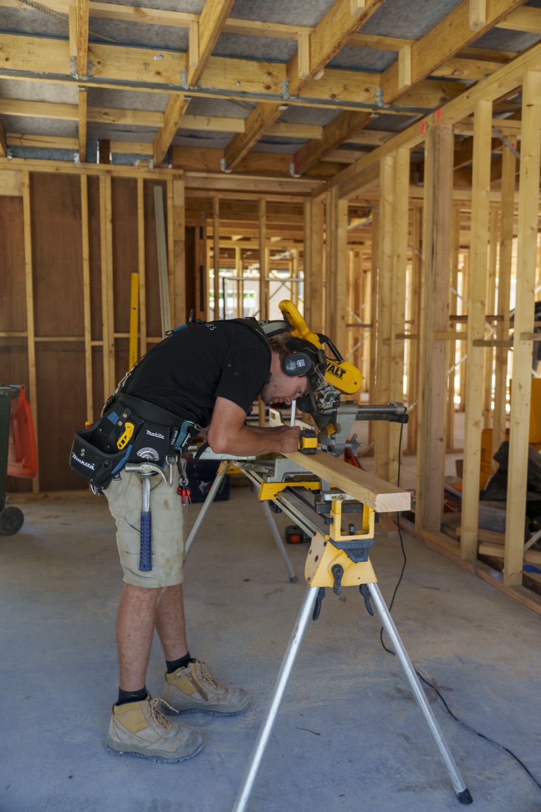 A carpenter cutting timber on a drop saw inside the frame