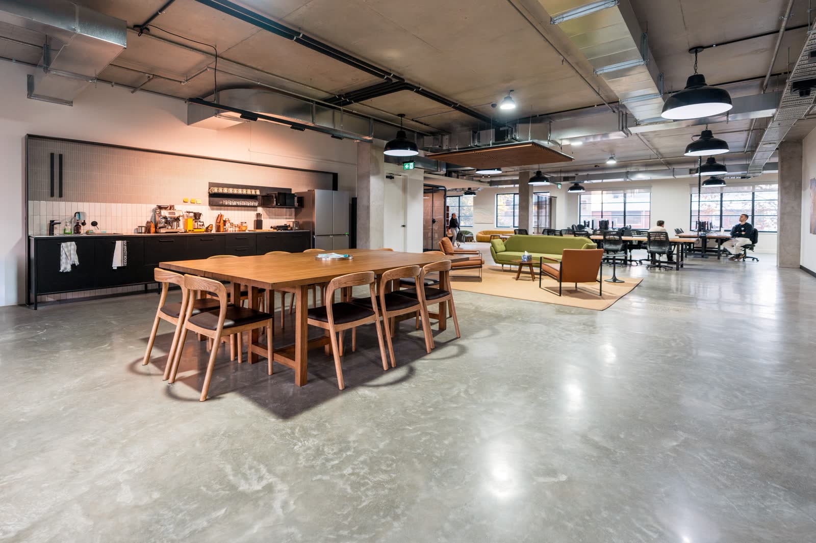 An office kitchen and dining area with timber table and pendant lighting
