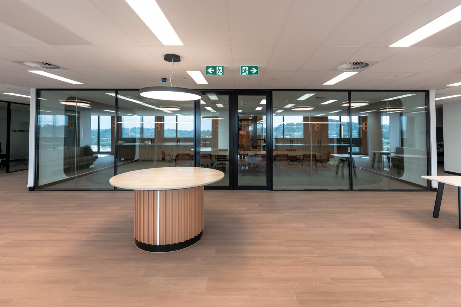 A curved timber banquette and glazed meeting rooms in an office fitout