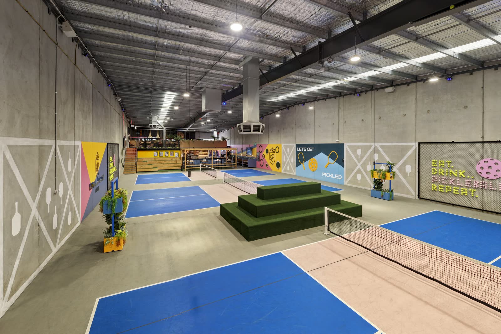 Blue and green pickleball courts under warehouse roofing at Royal Pickle Club