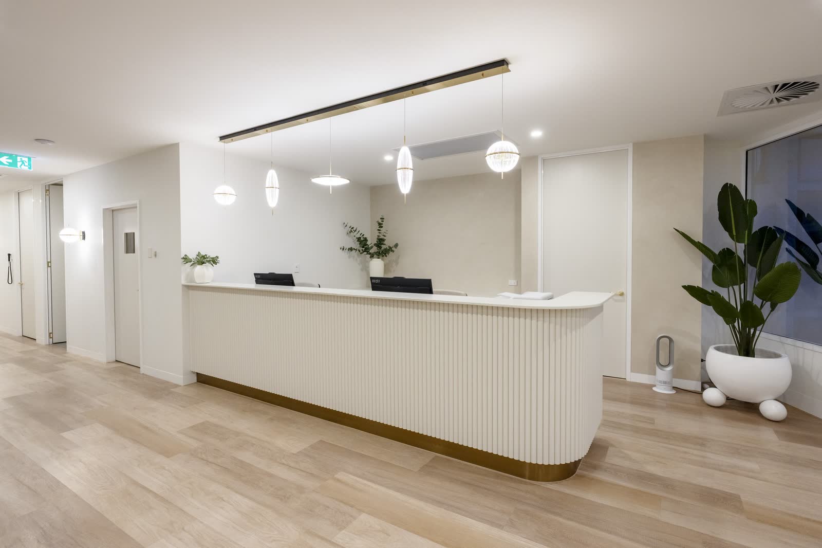 A curved reception desk and planting in a clinic foyer