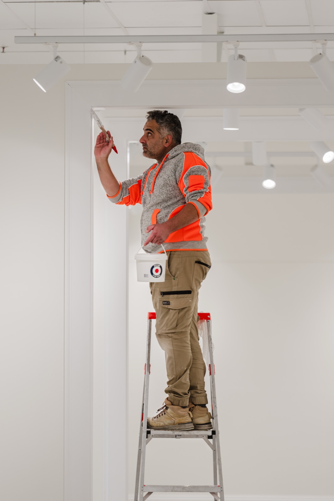 A tradesman on a ladder installing ceiling track in a new retail fitout