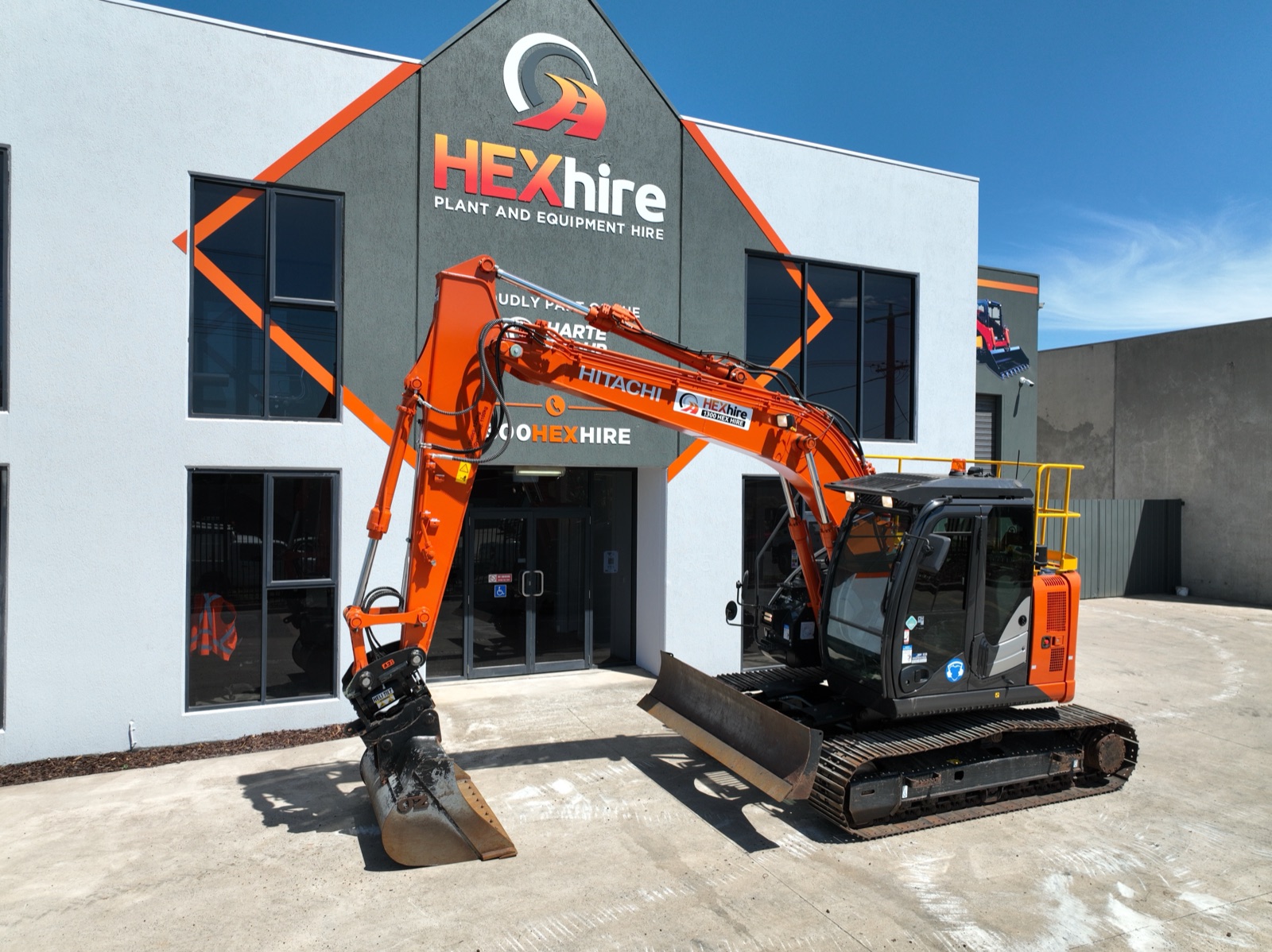 An excavator with a hydraulic attachment outside a plant hire depot