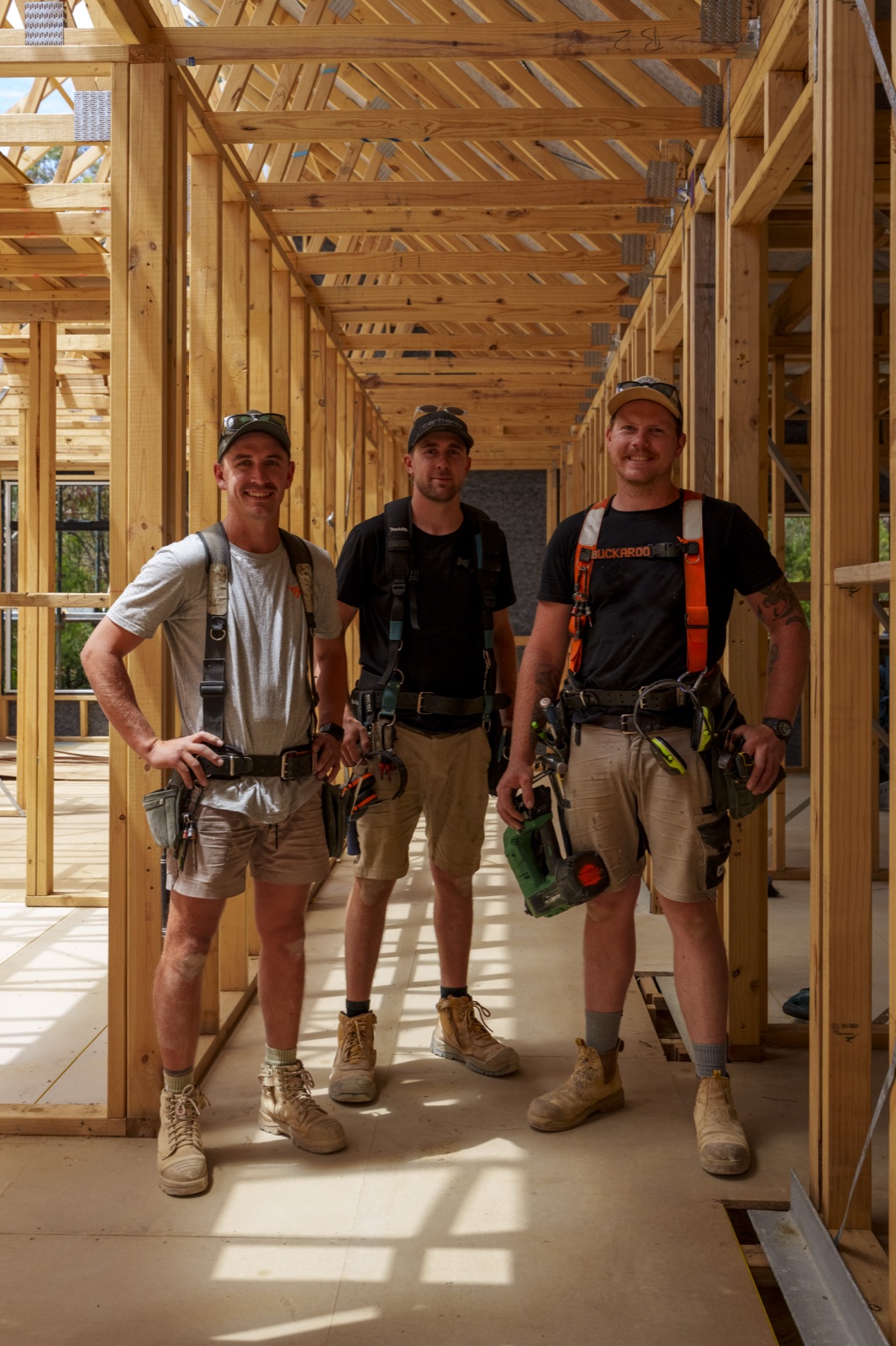 Three carpenters photographed in the framed hallway of a new build