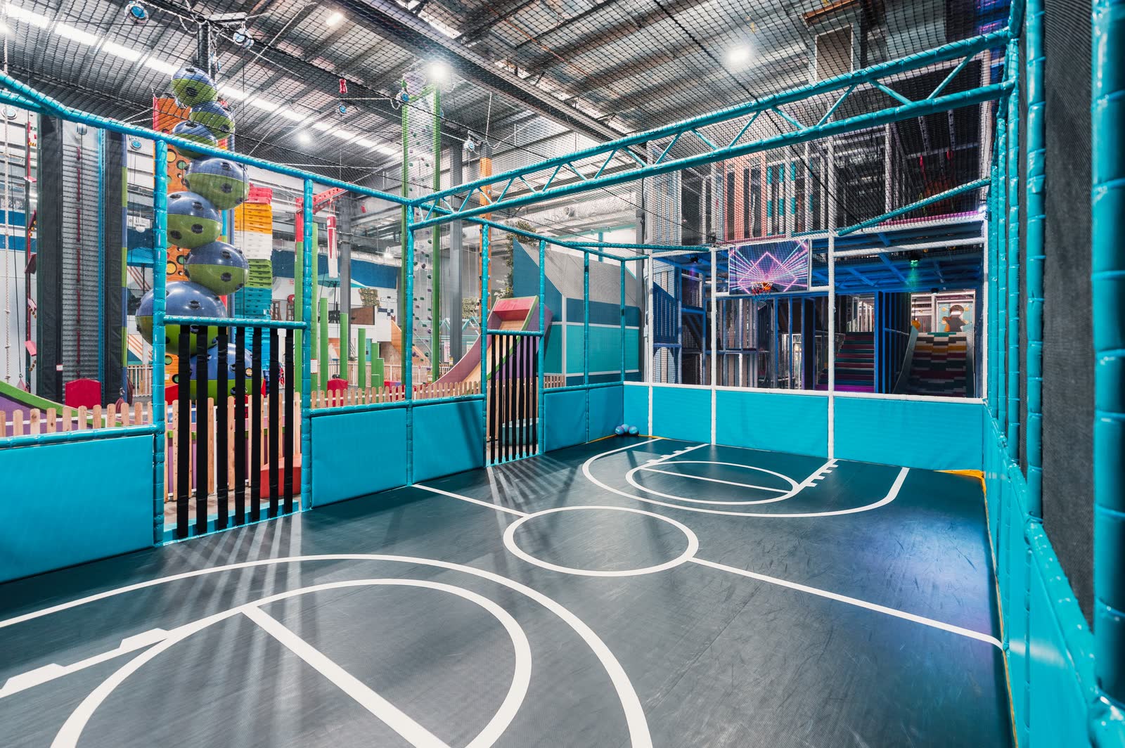 An indoor multi-sport court in teal caging at a family entertainment venue