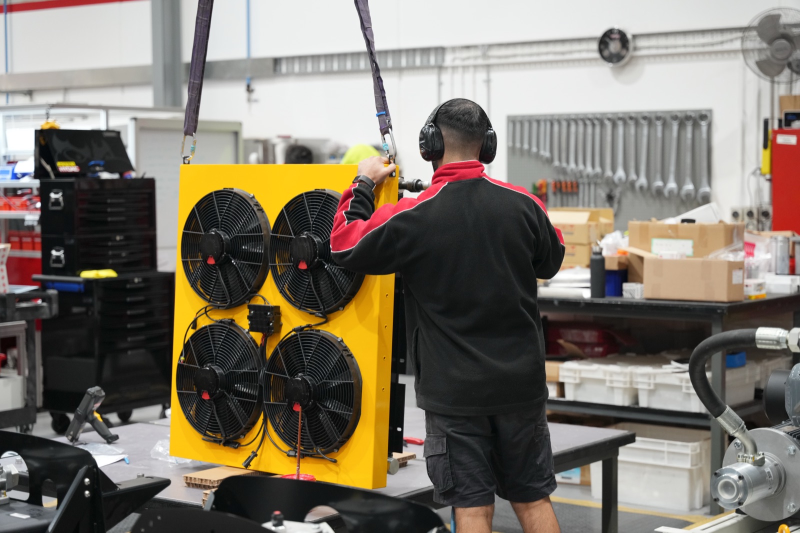 A worker assembling a yellow industrial cooling unit on the workshop floor