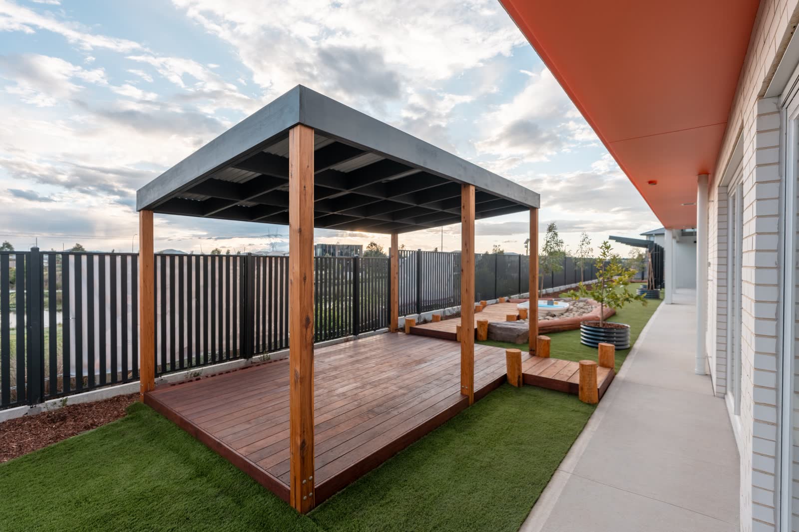 A timber pergola and deck in a landscaped courtyard at dusk