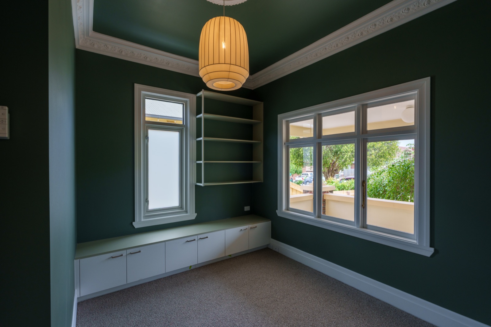 A study nook built into a deep green room with a window seat