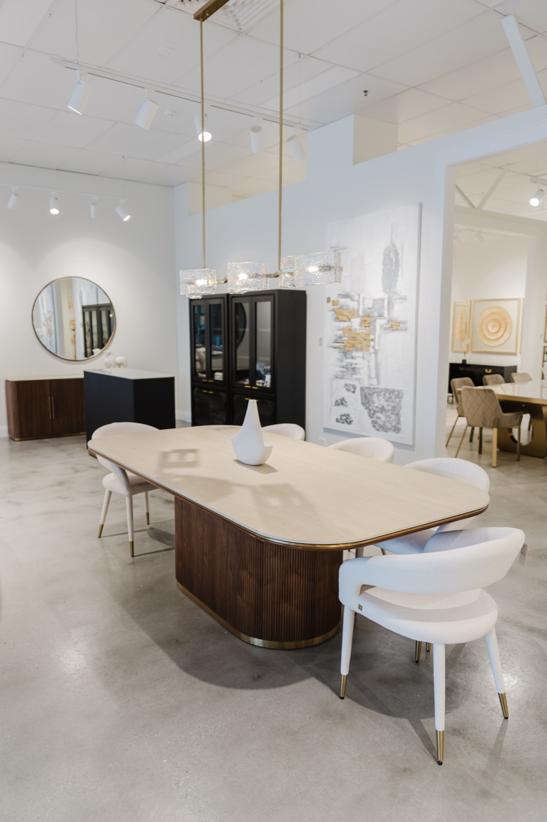A furniture showroom with a curved stone table, round mirror and styled vignettes