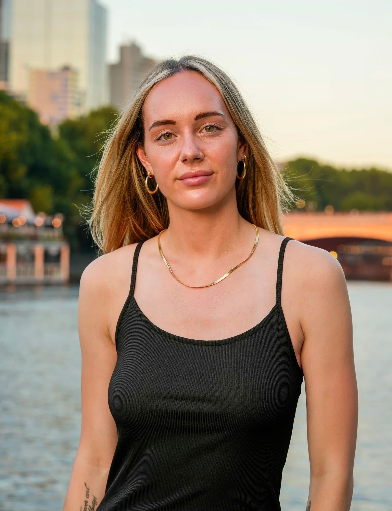 A creative portrait on the riverbank at golden hour with the city behind