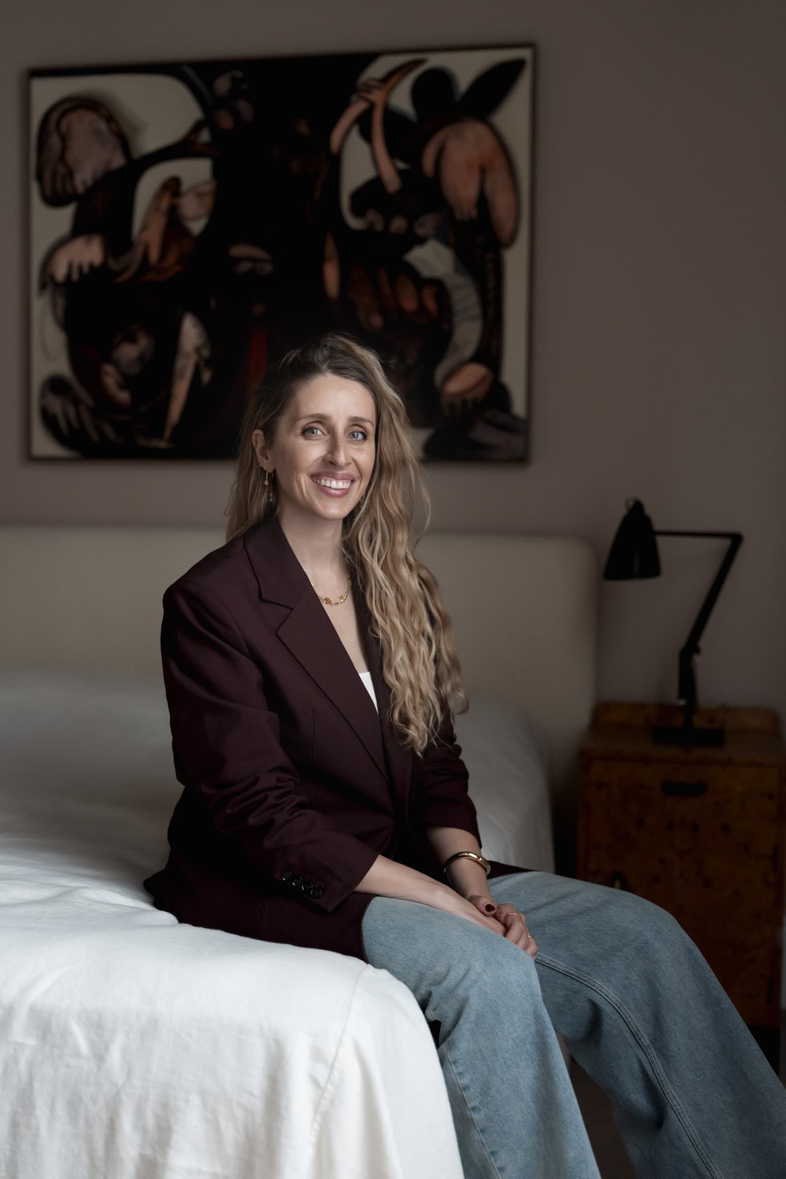 A relaxed indoor portrait seated below a bold framed artwork