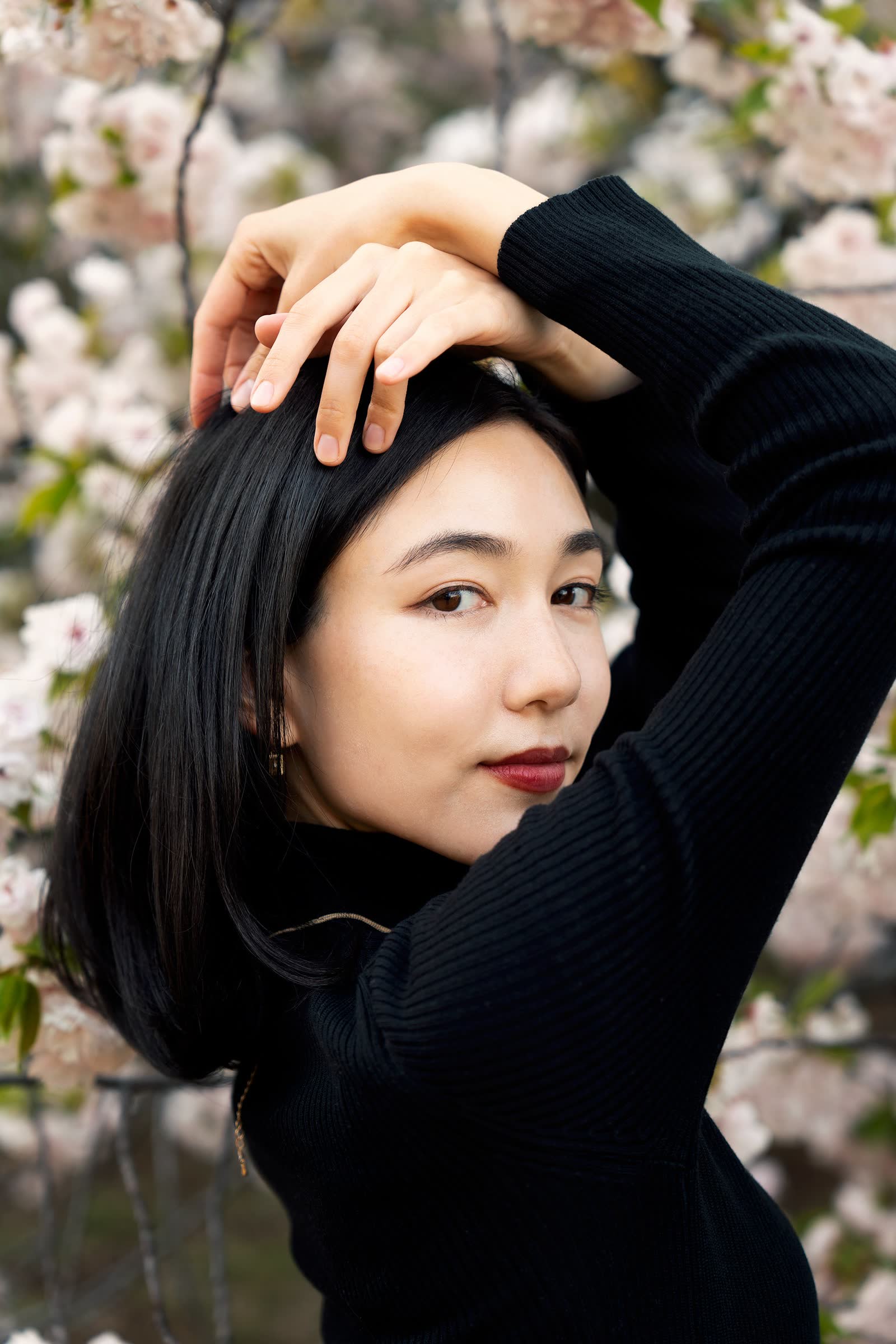 A creative portrait framed by cherry blossom in soft spring light
