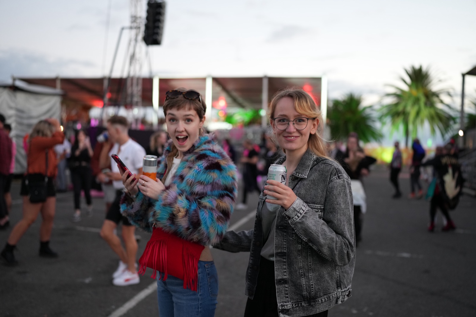 Two festival goers with drinks in the crowd