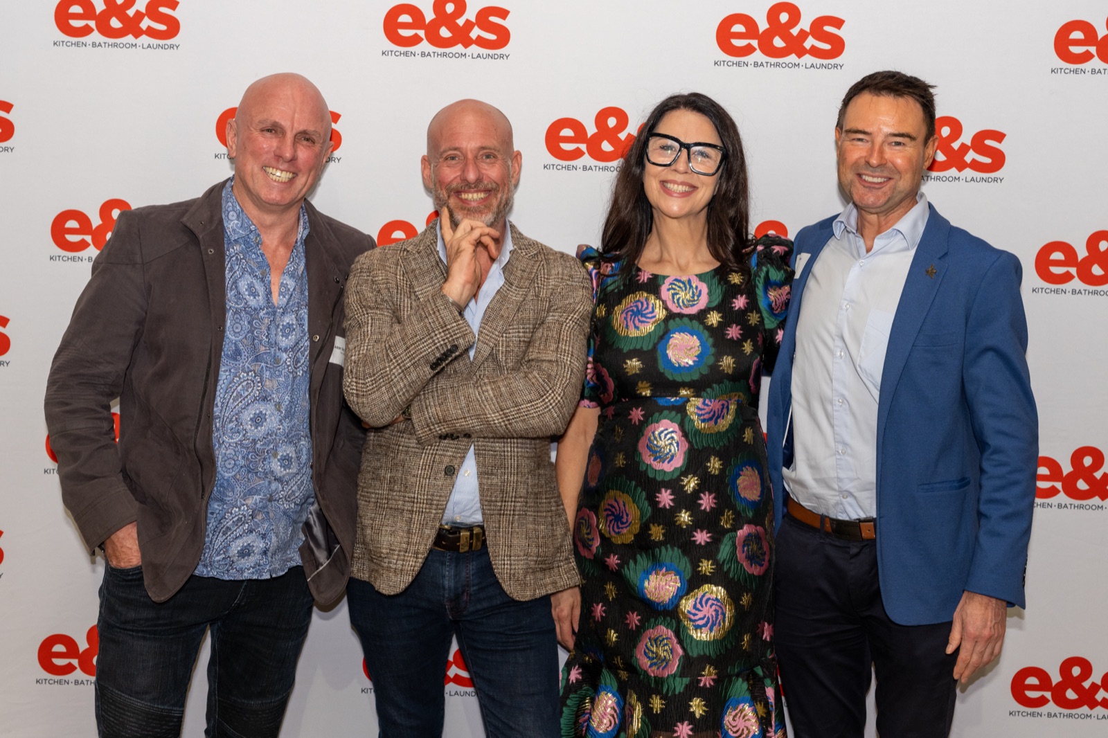 Four guests photographed at a branded media wall