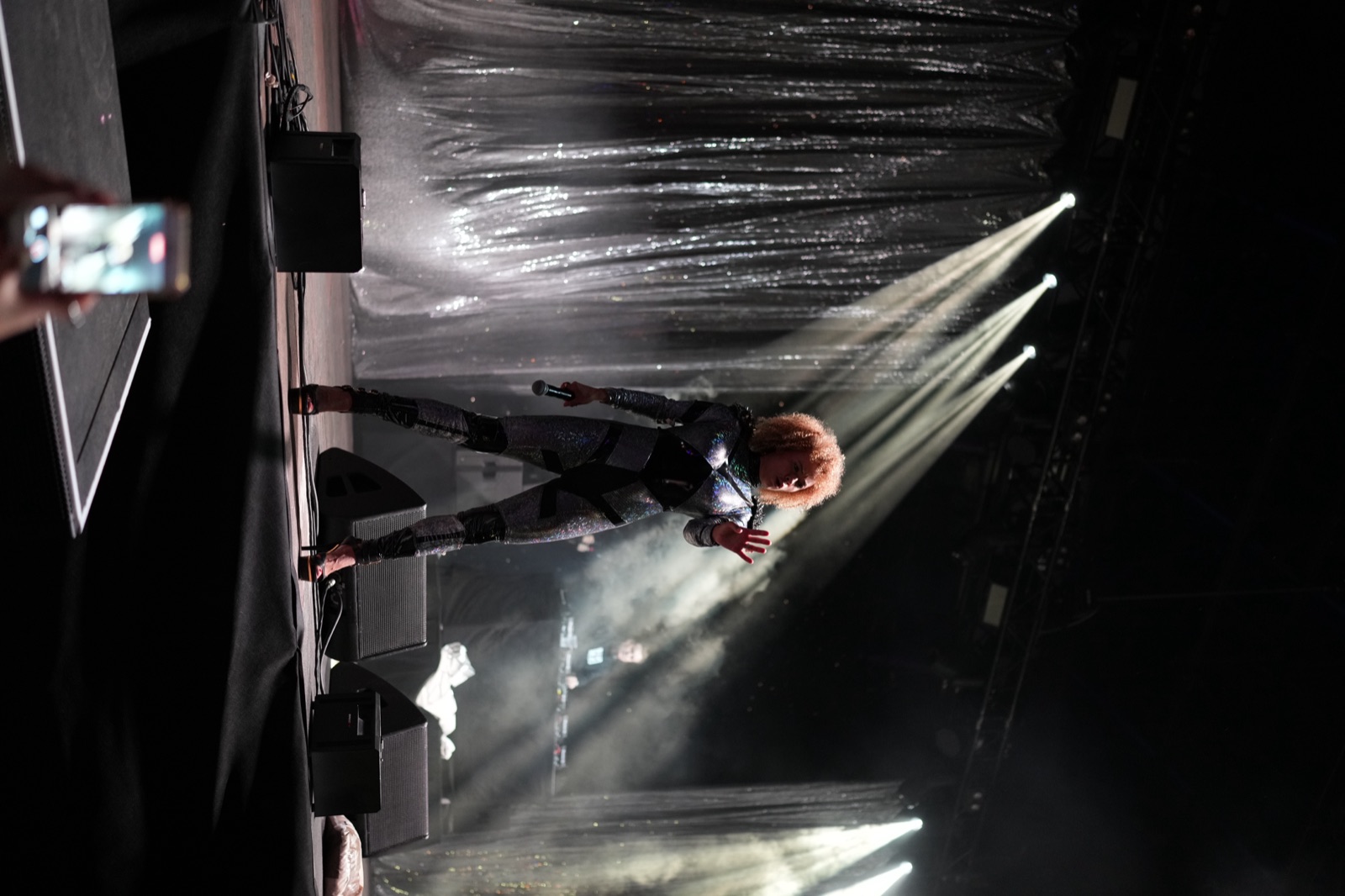 A performer suspended above the stage in the light beams