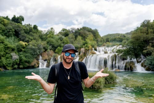 A man with arms spread in front of the Krka waterfalls, Croatia