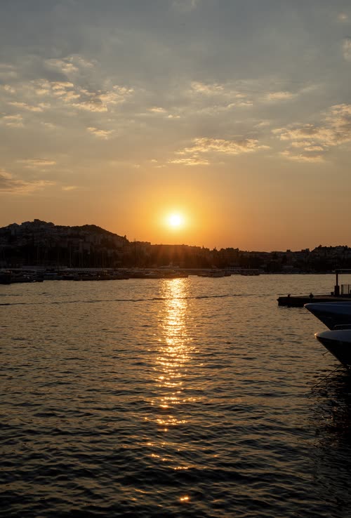 The sun setting over the harbour with a moored boat in silhouette, Croatia