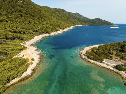 Aerial view of a narrow turquoise channel between two wooded Adriatic islands