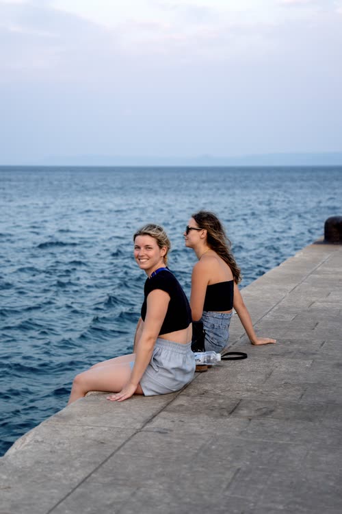Two women sitting on a stone jetty looking out over the Adriatic