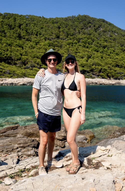 A couple standing on the rocks above clear water on a Croatian island
