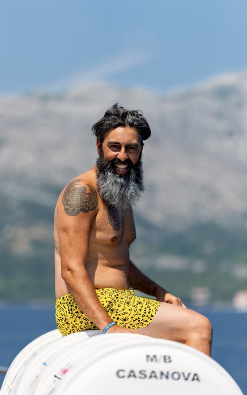 A bearded man sitting on the deck rail of the boat M/B Casanova, Croatia