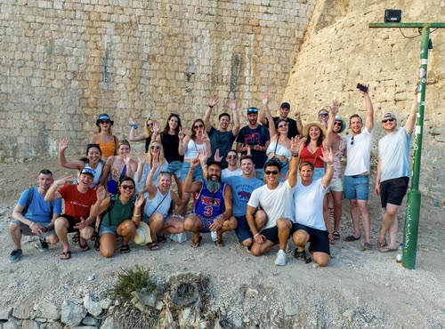 A tour group posed together against a stone fortress wall in Croatia
