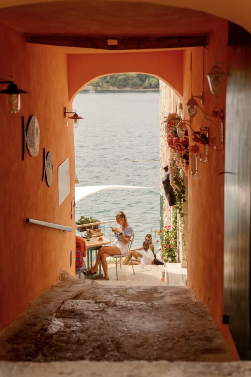 A view through an orange painted archway to the sea and a terrace, Croatia