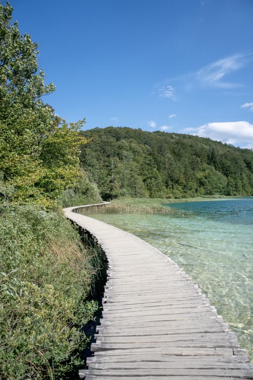 A timber boardwalk curving along the edge of a clear lake, Croatia