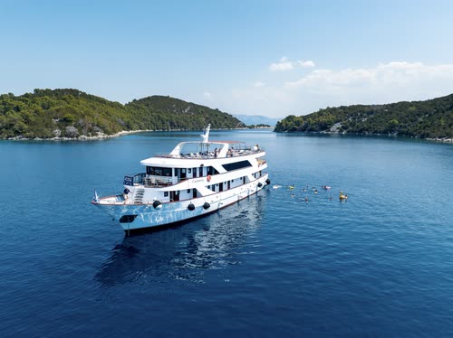A small white cruise ship anchored in a sheltered Adriatic bay, Croatia