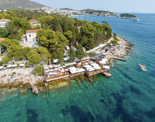 Aerial view of a beach club and pine-covered headland on Hvar, Croatia