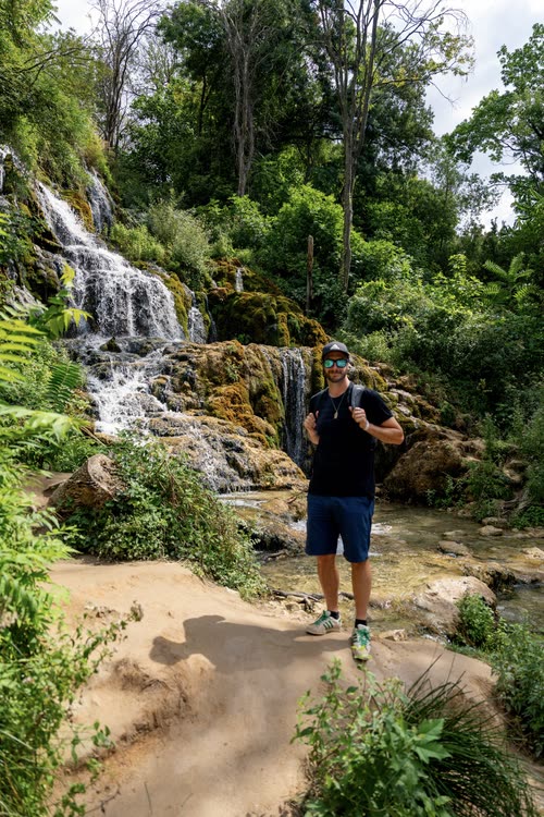 A man standing below the cascades at Krka National Park, Croatia