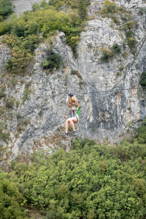 A woman riding a zipline across a limestone gorge above the trees, Croatia