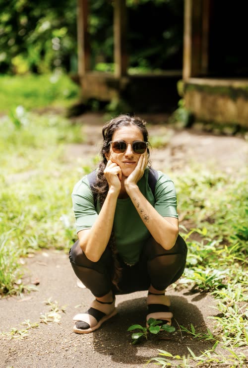 A woman crouching on a village path in the Indonesian countryside