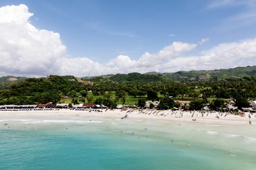 Aerial view of a curved white beach and turquoise bay in southern Lombok