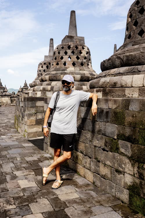 Jordy Scott leaning against the stone terrace wall at Borobudur, Java