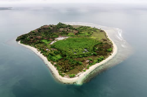 Aerial view of a Gili island with its beach and turquoise shallows, Lombok