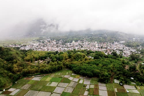Aerial view of a hillside town and its surrounding paddy fields under cloud