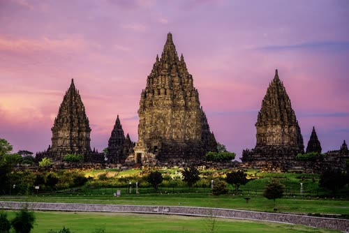 The towers of Prambanan silhouetted against a pink and purple dusk sky, Java