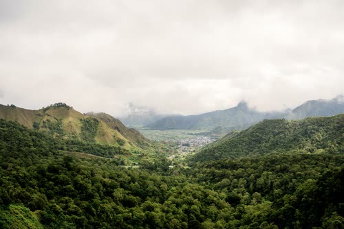 Cloud settling over steep forested ridges above a valley in Indonesia