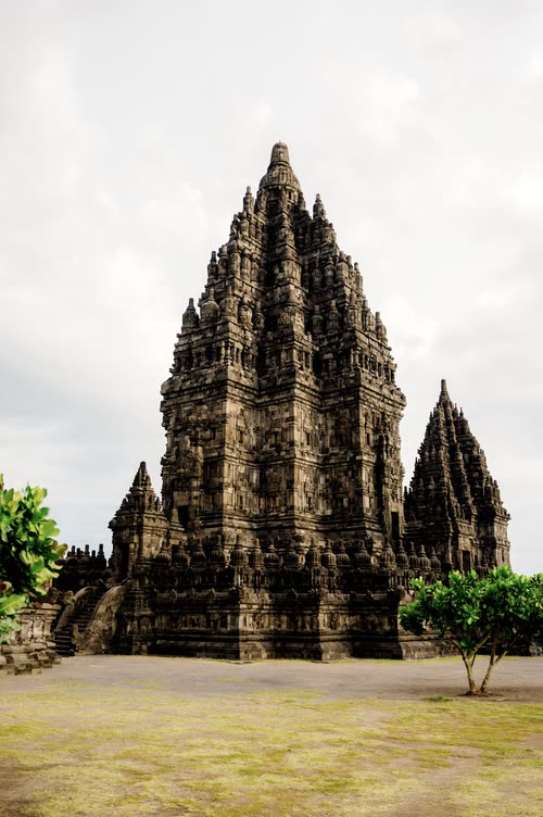 The carved stone spires of Prambanan temple under a white sky, Java