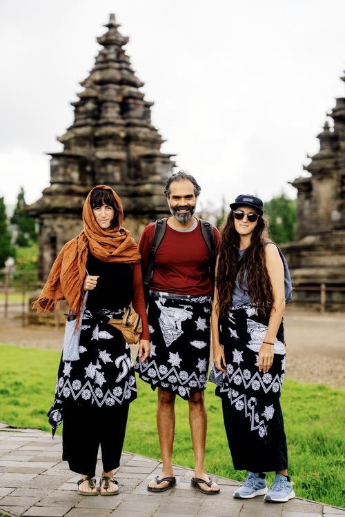 Three travellers in batik sarongs in front of the temples at Prambanan, Java