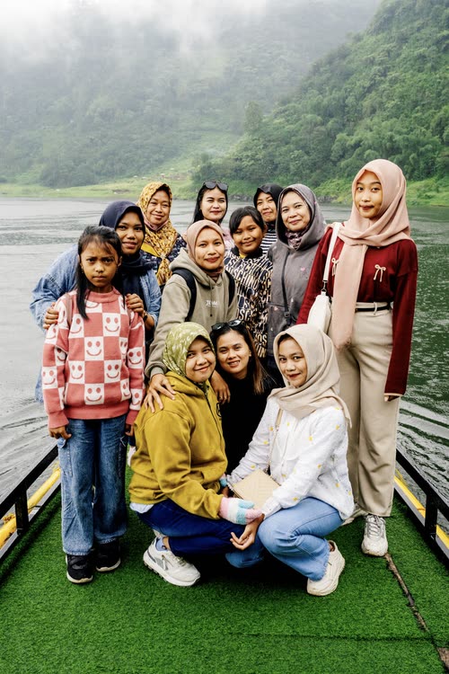 A group of young women posing together on a lakeside jetty in Indonesia