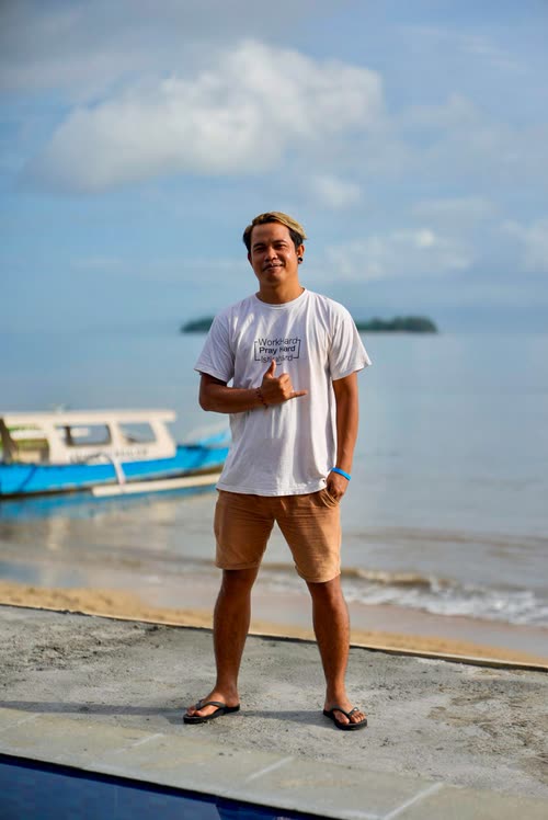 A man standing on a jetty beside a moored outrigger boat in Lombok